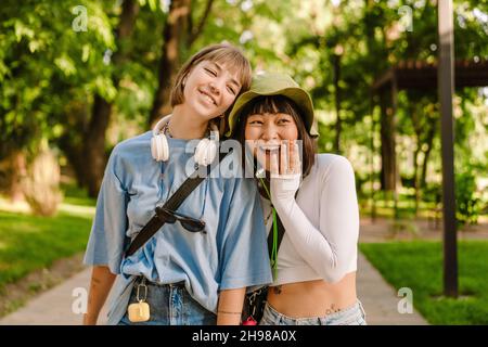 Multiracial deux femmes qui parlent et rient en marchant ensemble dans le parc Banque D'Images