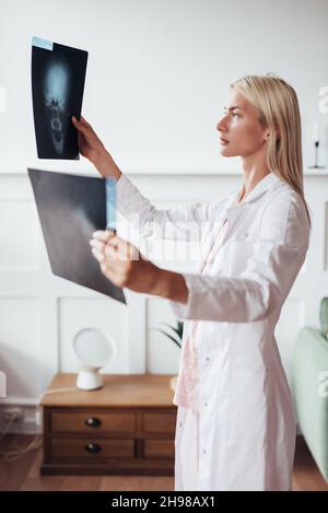 La femme chirurgien de traumatologie examine les acquisitions du crâne au bureau. Banque D'Images