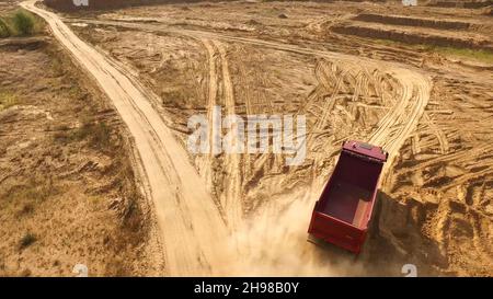 Le camion roule sur une route de carrière de sable.Scène.Vue de dessus de la conduite d'un camion-benne sur une route jaune en terre dans la campagne.Gros camions sur des chantiers de construction ou de carrière Banque D'Images