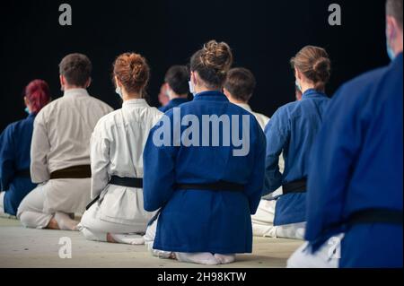 Les athlètes de Karate (ceinture noire) s'agenouillent en position Seiza, de derrière. Banque D'Images