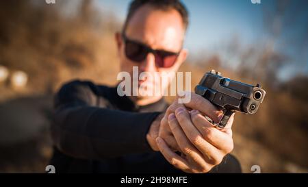 Agent de police et agent de protection du corps pointant un pistolet pour protéger de l'attaquant.Point de visée du canon vue de face extérieure Banque D'Images