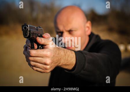 Agent de police et agent de protection du corps pointant un pistolet pour protéger de l'attaquant.Point de visée du canon vue de face extérieure Banque D'Images