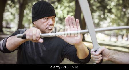 L'instructeur Lameco Astig Combatifs démontre les techniques de combat et les méthodes d'entraînement d'une seule épée et d'une arme à long couteau.Arts martiaux philippins EC Banque D'Images