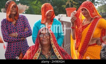 21 novembre 2021 Reengus, Rajasthan, Inde.Femme indienne âgée en robe traditionnelle avec lunettes et chaise avec des membres de la famille. Banque D'Images