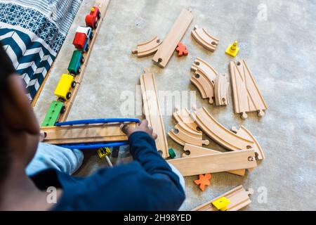 Garçon jouant avec le jouet de train.Garçon indien de 3 ans jouant avec une piste de train en bois et des trains Banque D'Images