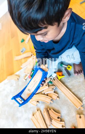 Garçon jouant avec le jouet de train.Garçon indien de 3 ans jouant avec une piste de train en bois et des trains Banque D'Images