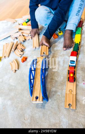 Garçon jouant avec le jouet de train.Garçon indien de 3 ans jouant avec une piste de train en bois et des trains Banque D'Images