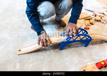 Garçon jouant avec le jouet de train.Garçon indien de 3 ans jouant avec une piste de train en bois et des trains Banque D'Images