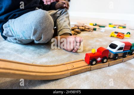 Garçon jouant avec le jouet de train.Garçon indien de 3 ans jouant avec une piste de train en bois et des trains Banque D'Images