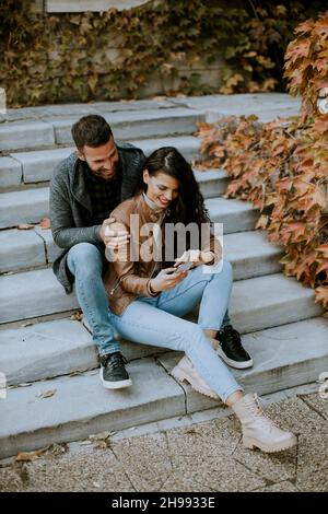 Beau jeune couple assis sur les escaliers extérieurs un jour d'automne Banque D'Images