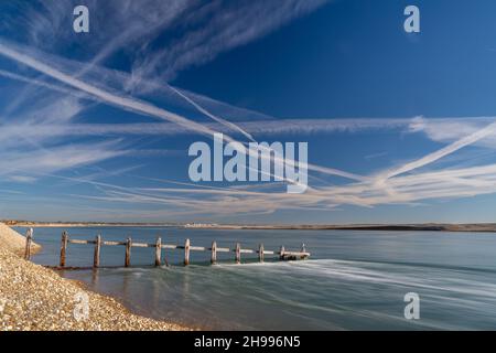 L'eau se précipitant dans l'entrée du port de Pagham avec un vieux grin regardant vers Bognor Regis sur un ciel bleu jour avec des sentiers con. Banque D'Images