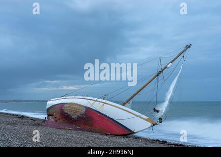 Un voilier abandonné et naufragé s'embarque sur la plage de l'église Norton, entre Pagham et Selsey, près de Chichester, dans l'ouest du Sussex. Banque D'Images