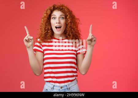 Magasin fascinant OMG, découvrez-le.Impressionnée excitée de bonne apparence redhead mauriquement émotive fille chute mâchoire étonnée heureux pointant vers le haut index des doigts Banque D'Images