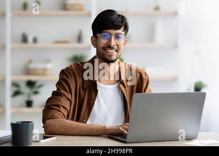 Portrait d'un homme indien joyeux travaillant sur un ordinateur portable Banque D'Images