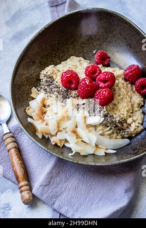 Un bol de flocons d'avoine frais avec des framboises de chia et des croustilles de noix de coco Banque D'Images