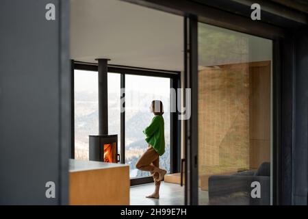 La jeune femme se tient près d'une cheminée dans une maison moderne sur la nature Banque D'Images