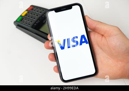 Système de paiement électronique Visa DEBIT.Un homme paie des biens et des services à l'aide d'une application mobile, d'un smartphone et d'un terminal de paiement POS.Novembre 2021, San Francisco, États-Unis Banque D'Images