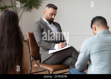 Couple assis à la séance de thérapie avec un thérapeute, homme prenant des notes Banque D'Images