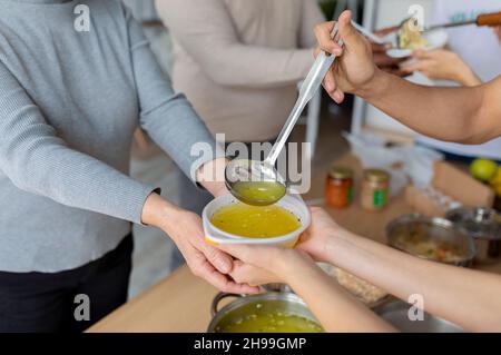 Aide pour les personnes âgées.Jeunes bénévoles servant de la soupe chaude pour les personnes âgées ou sans-abri dans un centre de dons caritatifs, à proximité Banque D'Images