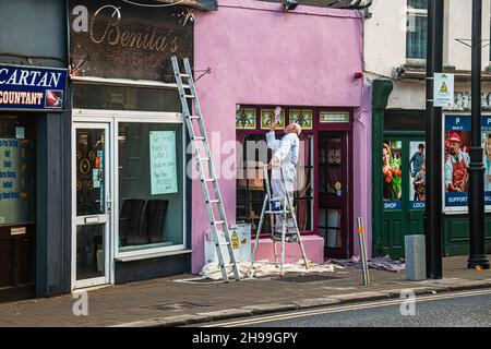 Peintre professionnel sur la façade du bâtiment de peinture en échelle de main Street à Arklow.Irlande. Banque D'Images