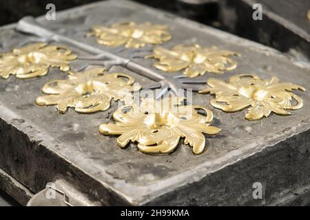 Fleur dorée élégante et branches grises moulées en fonte haute précision dans les ateliers de production traditionnels vue extrêmement rapprochée Banque D'Images