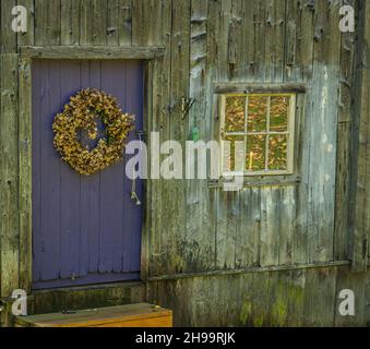 une couronne de fleurs séchées et une bougie dans la fenêtre accueillent les voyageurs à la porte sur une route de campagne Banque D'Images