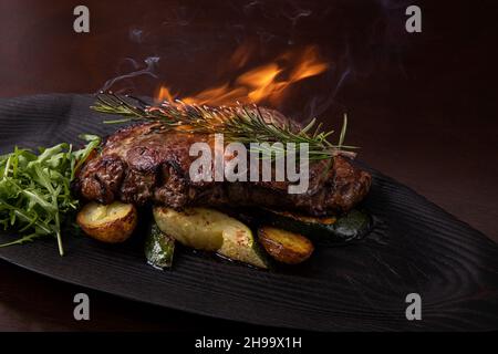 Steak de stripine grillé sur un plat noir. Avec pommes de terre frites et légumes Banque D'Images