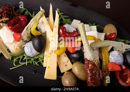Palette de nombreux types de fromage et quelques légumes, tomates, paprika, olives. Banque D'Images