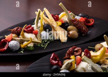 Palette de nombreux types de fromage et quelques légumes, tomates, paprika, olives. Banque D'Images