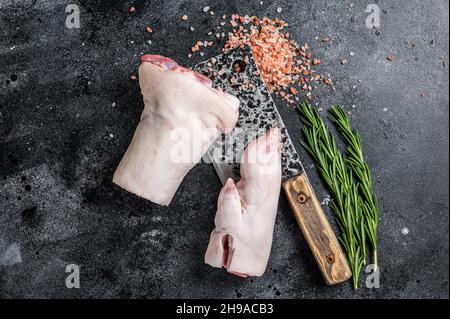 Boucherie - jarret de porc cru, porte-fusée, pieds sur une planche à découper.Arrière-plan noir.Vue de dessus Banque D'Images