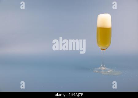 verre à vin mousseux plein avec beaucoup de mousse blanche devant le fond bleu, prise de vue en studio, espace réservé pour la saisie de texte propre Banque D'Images