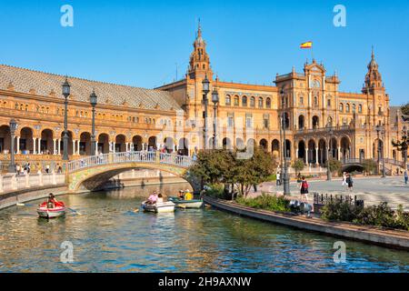 Plaza de Espana, les gens ramer bateau sur la douve avec des ponts représentant les quatre anciens royaumes de l'Espagne, Séville, province de Séville, Andalousie Aut Banque D'Images