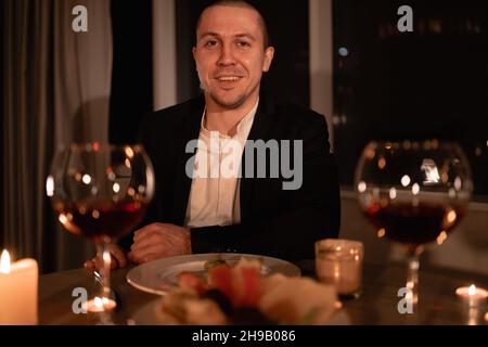 dîner romantique pour la saint-valentin, homme le 14 février à une table avec vin, un jour d'amour de vacances solitaire, portrait de l'homme millénaire avec des lunettes Banque D'Images