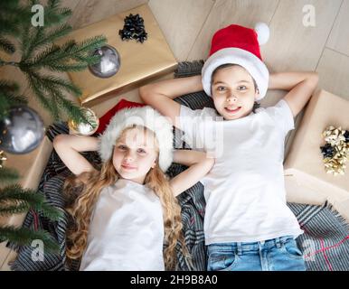 Les enfants se trouvent sous l'arbre et rêvent.Arbre de Noël dans le grand salon. Banque D'Images