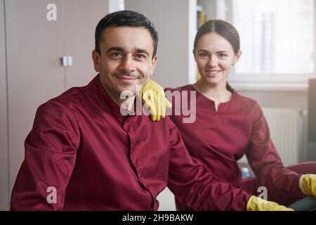 Le personnel d'entretien souriant dans les uniformes pose pour l'appareil photo sur le lieu de travail Banque D'Images