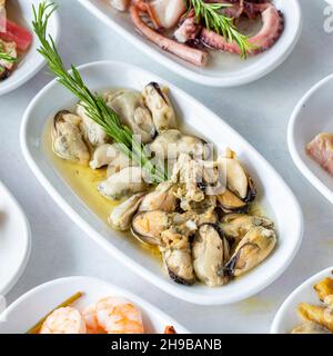 Ensemble de plats de fruits de mer.Fruits de mer sur une assiette.Sur fond blanc en bois.Moules marinées à concentration sélective.Crevettes, lakerda, salade de poulpes, moules Banque D'Images