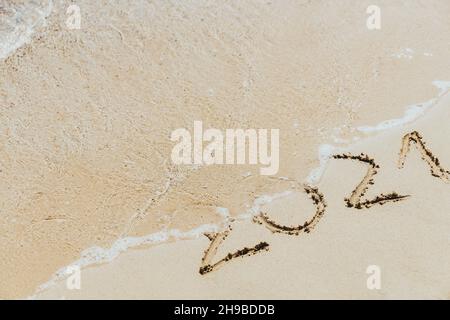 Les vagues délavent l'inscription sur le sable 2021.Concept de l'année sortante Banque D'Images