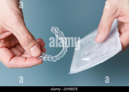 Homme tenant l'outil d'alignement transparent et son emballage.Concept d'orthodontie Invisalign Banque D'Images