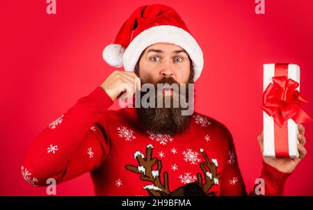 Cloches de jingle. Fête d'hiver. Homme mature fêtant la nouvelle année. Boxeur en pull Noël. Homme surpris avec barbe en chapeau de père noël Banque D'Images