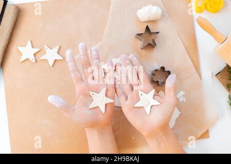 Les mains des femmes ont deux biscuits sous la forme d'étoiles de Noël.Pose à plat.Repas maison de fête. Banque D'Images