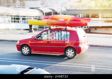 Voiture rouge sur la rue transportant deux kayaks sur le toit Banque D'Images