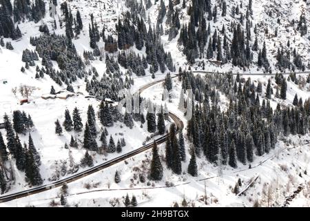 Vue aérienne de la forêt enneigée avec une route. Banque D'Images