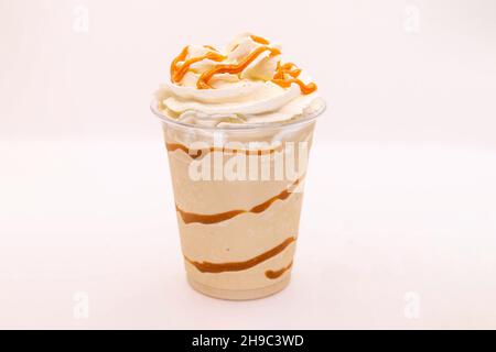Fritpe aromatisée au caramel servie dans une tasse en plastique avec crème fouettée et vinaigrette. Banque D'Images