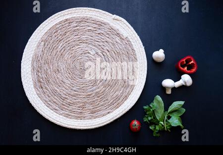 Napperon en maille vide près des champignons, de la tomate, du paprika, du persil, de la menthe,idée de menu de concept de service sur fond noir isolé Banque D'Images