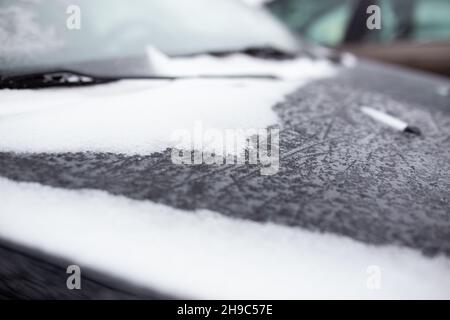 Le capot de la voiture est recouvert de neige dans le froid dans de beaux flocons de neige.Gros plan Banque D'Images