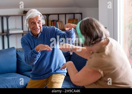 Couple senior à la maison.Un vieil homme charmant et une vieille femme attrayante apprécient de passer du temps ensemble.Amusez-vous et dansez avec un casque sans fil Banque D'Images