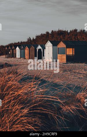 Cabines de plage dans une rangée au-delà des dunes de sable Banque D'Images