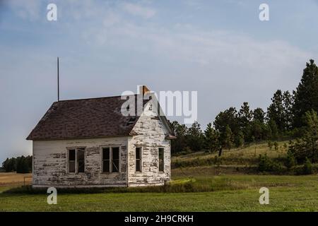 Un ancien a abandonné une maison d'école d'une pièce dans la prairie du Dakota du Nord dans la soirée. Banque D'Images