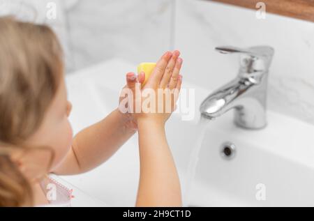 L'enfant lave ses mains sous le robinet. Banque D'Images