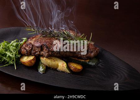 Steak de stripine grillé sur un plat noir. steak avec pommes de terre frites et légumes Banque D'Images